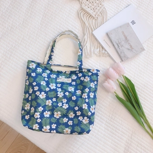 Detail of floral canvas tote bag with blue base and white flower pattern and cloth tag