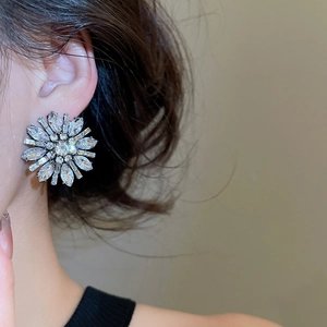 Detail of luxury flower stud earrings with sparkling zircons worn by a female model