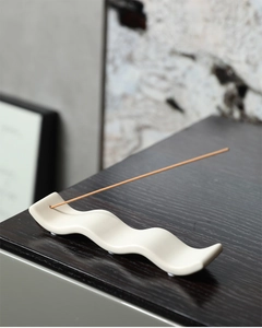 Porte-encens minimaliste en céramique ondulée blanc crème sur surface en bois