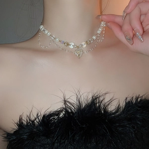 Gros plan d'un collier multicouche doré avec cœur et perles sur un mannequin en noir