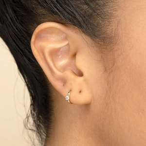 Aros minimalistas de oro de 18k con circón, aguja de plata s925 en la oreja del modelo