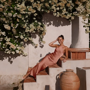 Detailed backless design of a rose gold satin dress worn by a model in sunlight