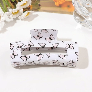 Detailed view of rectangular PVC hair claw clip with black and pink butterfly patterns