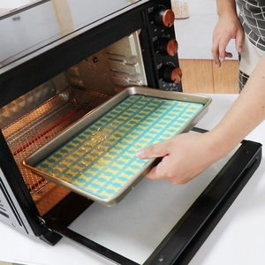 Detail showing a hand placing the silicone baking mat into a black electric oven