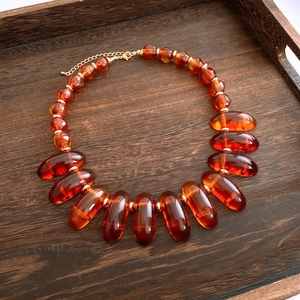 Detail view of amber resin beads and gold metal links on a dark wood tray