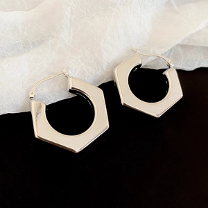 Close-up of geometric silver-finished hexagonal hoop earrings with polished metal texture