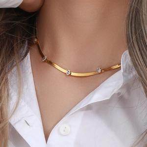 Gold herringbone necklace with oval clear zircons worn on model with white shirt