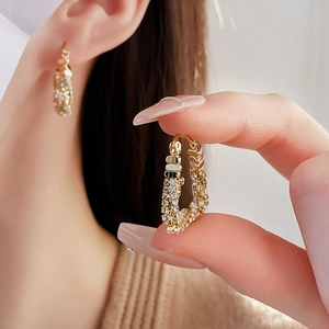 Detail of gold U-shaped earrings with pavé cubic zirconia showing the fine craftsmanship