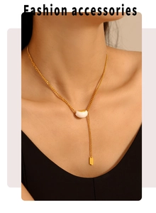Detail of gold necklace with white bean pendant and Lucky engraved tag on model