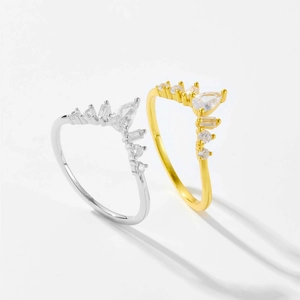 Detailed view of gold and silver V-shaped crown rings with sparkling white zircons
