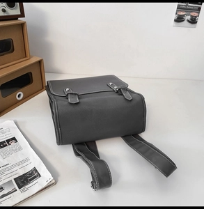 Detail view of the back and base of a grey faux leather backpack with white stitching