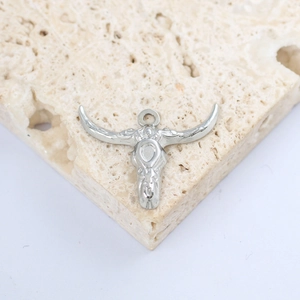 Detail of silver bull skull pendant with horn textures on a natural stone surface