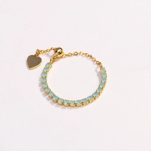 Detail of adjustable gold chain ring featuring light blue zircon and heart charm