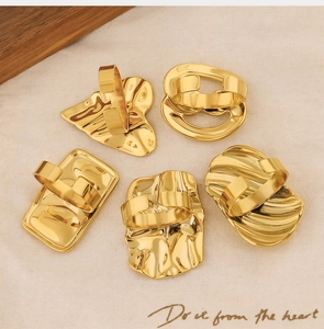 Detailed view of five 18k gold irregular geometric rings with shell textures on beige fabric