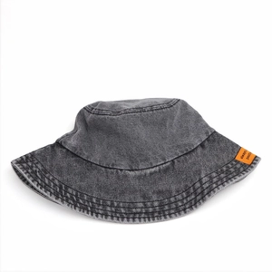 Dettaglio del cappello a secchiello in denim lavato con cuciture rinforzate e etichetta arancione