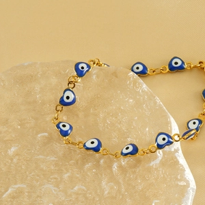 Detail of 18K gold-plated heart evil eye bracelet on an ice-cracked glass display