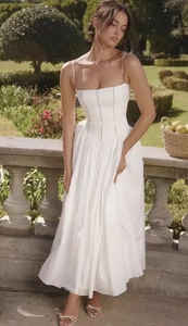 Close-up of white sundress with lace patchwork and high-waist design in garden