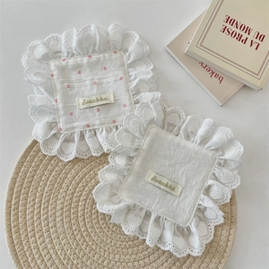 Detail of square cotton placemats with heart patterns and elegant white lace borders