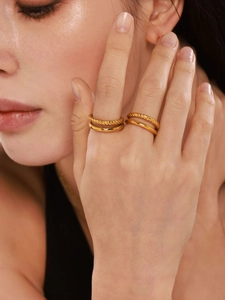 Close-up of stacked 18k gold plated stainless steel twisted and smooth band rings on finger