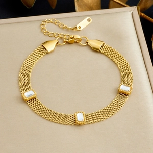 Détail d'un bracelet en maille dorée avec trois pierres rectangulaires et fermoir mousqueton