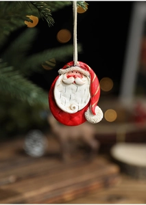Close-up of a hand-painted resin Santa Claus ornament hanging on a festive Christmas tree