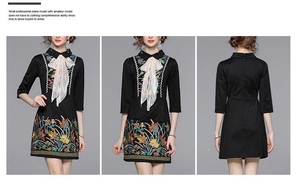 Detail view of black dress featuring exquisite floral embroidery and silk bow neckline