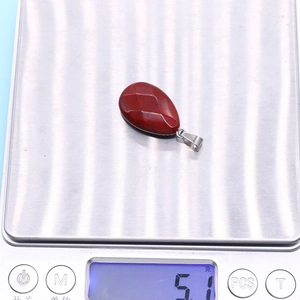 Detailed view of faceted red gemstone pendant weighing 5.1g on a digital scale