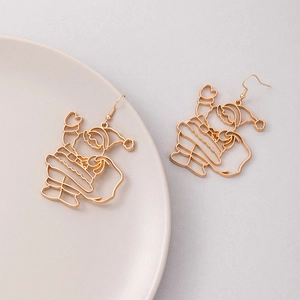 Vue détaillée de boucles d'oreilles Père Noël dorées sur un plateau rose clair élégant
