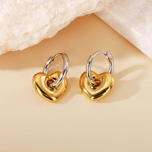 Detail of two-tone heart pendant hoop earrings in gold and silver polished metal