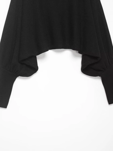 Detail of black knit sweater featuring long ribbed cuffs and puffy lantern sleeves