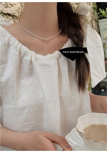 Close-up of 3mm freshwater baby pearls with a small 14K gold bead on a choker necklace