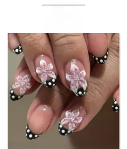 Gros plan d'ongles French press-on avec fleurs roses 3D et motifs à pois blancs