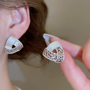 Macro shot of geometric triangular earrings with white stripes and leopard print panels