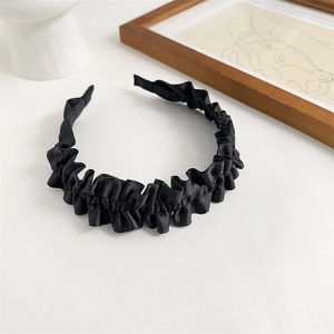 Close-up of black pleated wave-shaped fabric headband with soft texture on a clean background