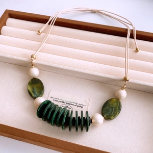 Detail of vintage beaded necklace with green resin stones and pearls in a wooden jewelry box