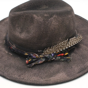 Detail of dark brown wool felt fedora with vintage ribbon, leather cord and feather accent