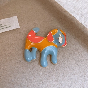 Macro shot of colorful enamel beagle dog brooch with gold trim on brown background