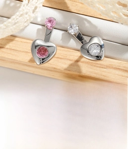 Macro shot of silver heart navel rings with pink and white zircon in titanium steel