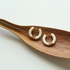 Artistic close-up of French enamel hoop earrings on a dry leaf background