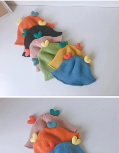 Detail of colorful knitted baby bucket hats with cute 3D heart-shaped accessories