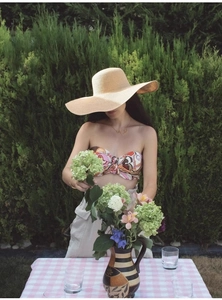 Détail d'un chapeau de soleil en paille à large bord avec un haut bustier imprimé