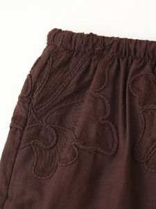 Détail de la taille élastique marron foncé avec broderie florale sur le pantalon