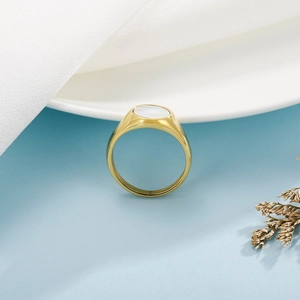 Macro detail of golden geometric ring featuring a polished white shell inlay surface