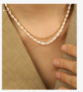 Detail shot of elegant double-layered necklace with freshwater pearls and gold beads on a model