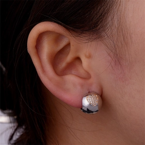 Detail of silver twisted hoop earrings with gold pavé crystal heart on female model