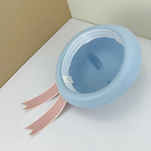 Detail view of light blue wool hat interior with 100% polyester label and pink ribbons
