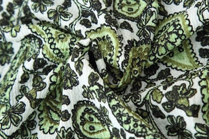 Close-up of green and white paisley print fabric with crushed pleat texture and floral pattern