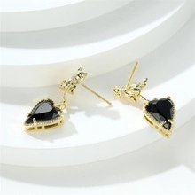 Macro view of gold cat earrings with cubic zirconia and black heart shaped gemstone