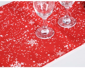 Detail of red Christmas table runner featuring white snowflake patterns on linen texture