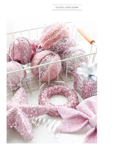 Close-up of pink Christmas ball ornaments with glitter and velvet in a white wire basket